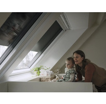 Eine Mutter und ihr Kind schauen durch ein Dachfenster mit Rollladen