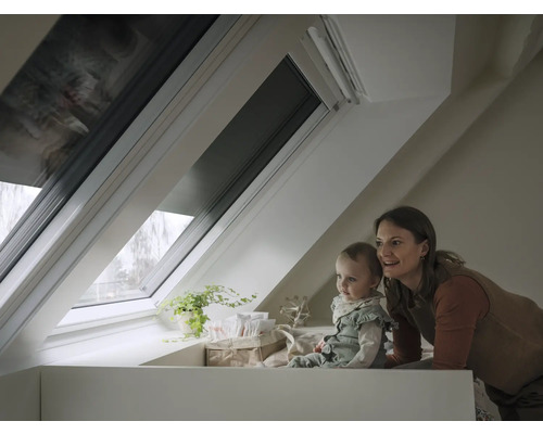 Dachfenster mit Verdunkelungsrollo in einem hellen Dachzimmer mit einer Frau und einem Baby