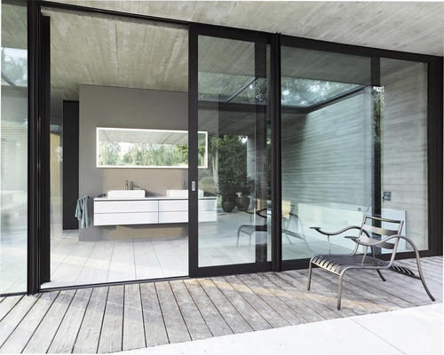 Badezimmer mit Waschtisch, Spiegel und Schiebetüren zur Terrasse mit Sitzgelegenheit