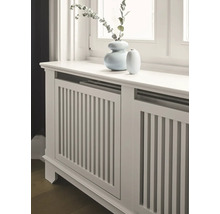 Heizkörperverkleidung aus Holz mit vertikalen Lamellen und zwei Vasen auf der Oberseite.