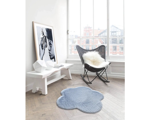 Wohnzimmer mit Teppich in Wolkenform, Sitzbank, Sessel und gerahmtem Poster