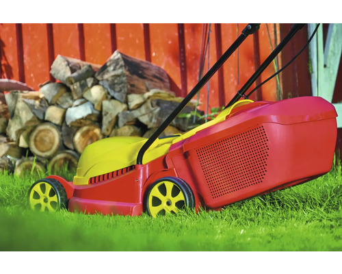 Rasentrimmer im Garten mit Holzstapel