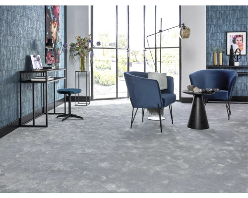 Wohnzimmer mit grauer Teppichfläche, blauen Sesseln und schwarzen Möbeln vor Fensterfront