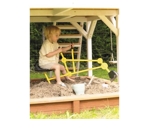 Junge spielt mit einem gelben Bagger im Sandkasten unter einem Spielturm
