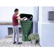 Mann befüllt eine Regentonne mit Gießkanne und Eimer.