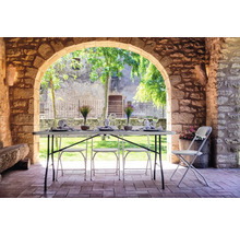 Gedeckter Tisch und Stühle auf einer Terrasse unter einem Steingewölbe
