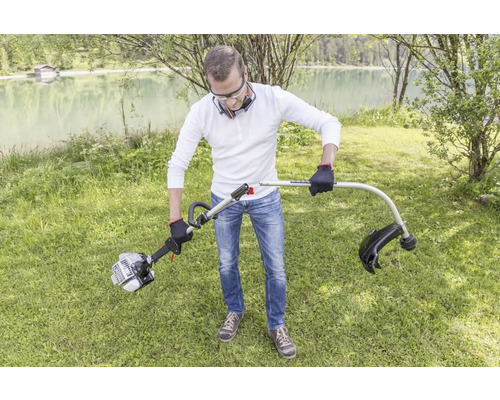 Eine Person montiert einen Rasentrimmer im Garten.
