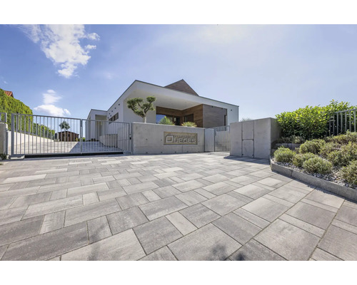 Einfahrt mit Betonpflastersteinen vor einem modernen Haus mit Tor