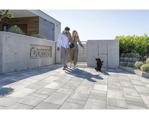 Gepflasterte Einfahrt mit Paar und Hund vor einem Haus