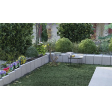 Gestalteter Gartenbereich mit Rasenfläche, Sitzgelegenheiten und Blumenbeet