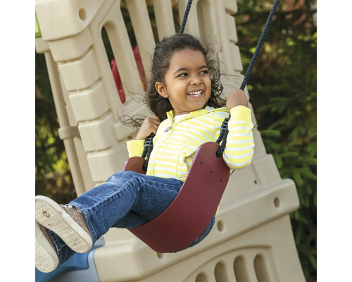 Ein lachendes Kind schwingt auf einer Schaukel im Garten.