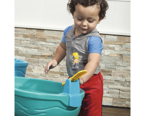 Ein Kind spielt mit einem Wasserspieltisch im Freien