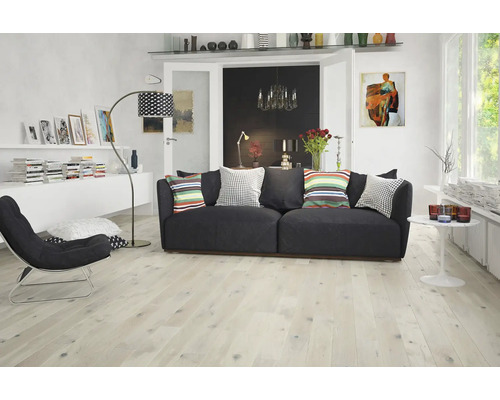 Wohnzimmer mit Sofa, Sessel, Stehlampe und hellem Holzboden
