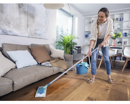 Frau wischt Holzboden mit einem Mopp in einem Wohnzimmer