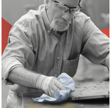 Ein Mann reinigt eine Werkbank mit einem Tuch.