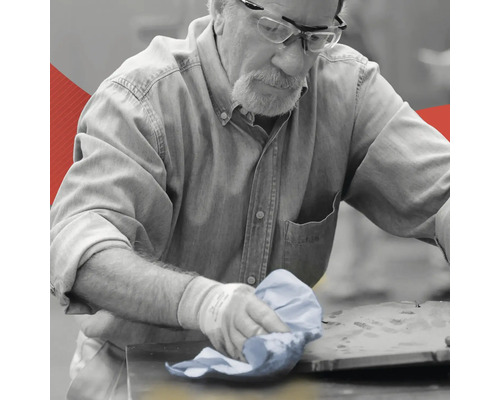 Ein Mann reinigt eine Werkbank mit einem Tuch.