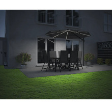 Beleuchteter Gartensitzplatz mit Sonnenschirm, Tisch und Stühlen in der Abenddämmerung.