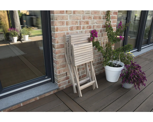 Zusammengeklappter Gartentisch aus Holz neben Blumen auf einer Terrasse