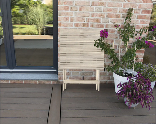 Klapptisch aus Holz auf einer Terrasse neben Pflanzen