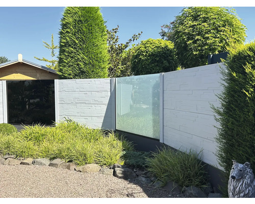 Gartenzaun mit Steinoptik und Glaselementen vor Garten