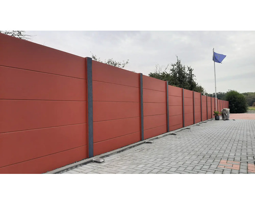 Langer Betonzaun mit grauen Säulen und Pflastersteinen