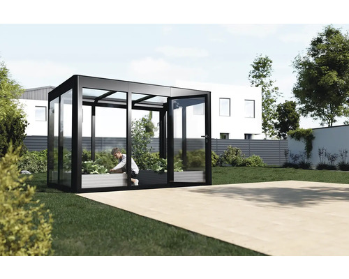 Gewächshaus aus Glas und Metall mit einer Person, die darin Pflanzen pflegt, im Garten