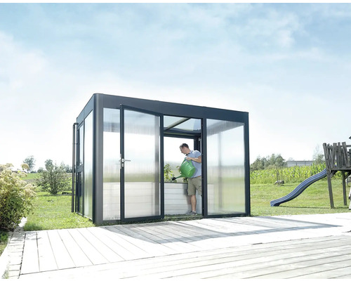 Gewächshaus mit transparenter Verglasung und einer Person, die Pflanzen gießt