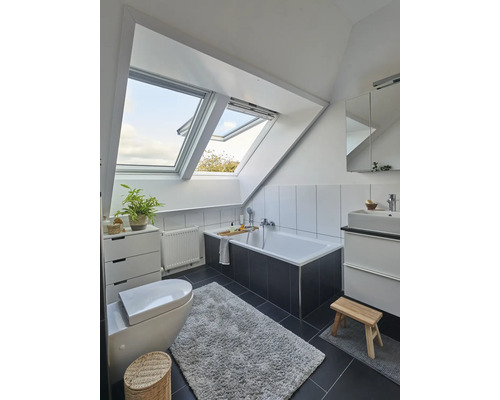 Helles Badezimmer mit Dachfenstern, Badewanne, Waschbecken und Toilette