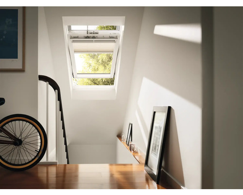 Dachfenster mit geöffnetem Fenster und Jalousie in einem hellen Treppenhaus.