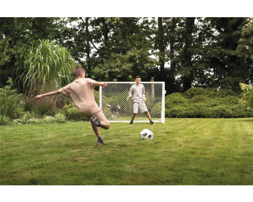 Zwei Jungen spielen mit einem Fußballtor im Garten.