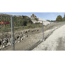 Bauzaun entlang einer Baustelle mit einem Bagger im Hintergrund