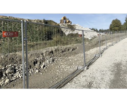 Bauzaun entlang einer Baustelle mit einem Bagger im Hintergrund