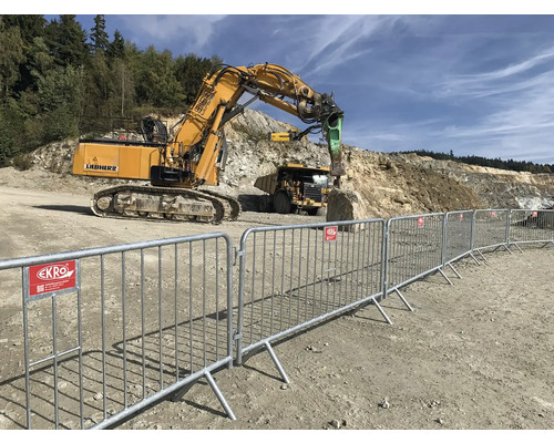 Baustellenszene mit Absperrgitter, Bagger und Muldenkipper