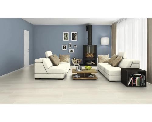 Heller Wohnraum mit Fliesenboden, Sofas und Kaminofen.