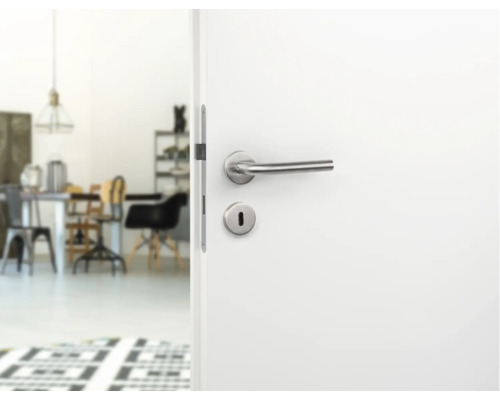 Geöffnete weiße Tür mit silberner Türklinke und Blick in einen hellen Raum