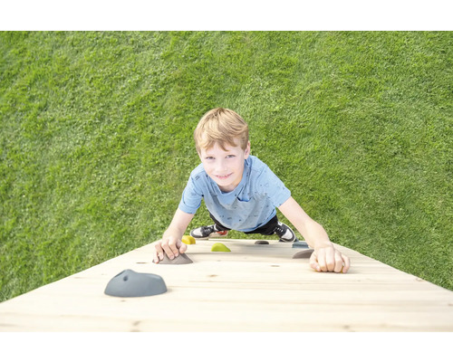 Junge klettert an einer Kletterwand im Garten