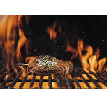 Ein Steak wird auf einem Grill mit Flammen gegrillt.