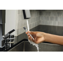 Eine Hand hält ein Thermometer unter einen Wasserhahn.