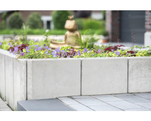 Hochbeet aus Betonsteinen mit Pflanzen und Dekoration im Garten.