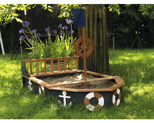 Sandkasten in Bootsform mit Steuerrad, Flagge und maritimen Dekorationen im Garten