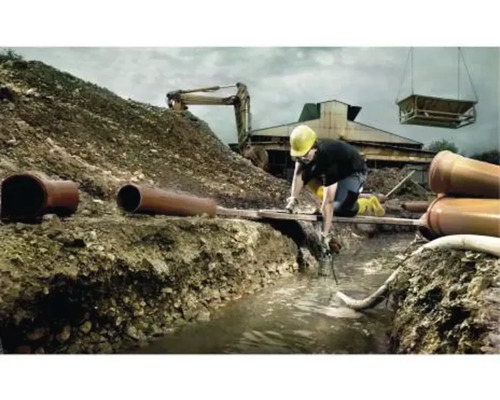 Baustelle mit Arbeiter, Bagger und Rohren