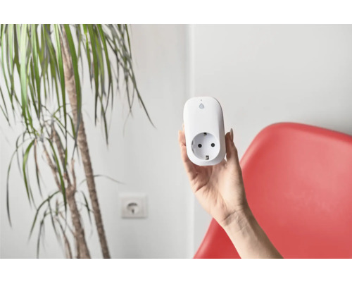 Eine Hand hält eine weiße smarte Steckdose.