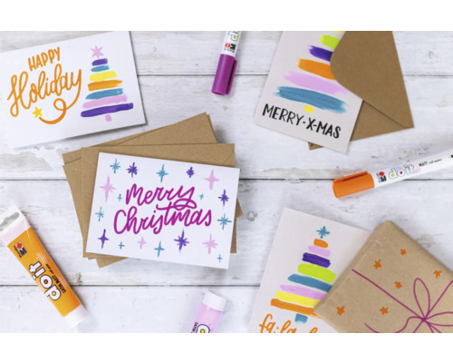 Dekorative Weihnachtskarten mit Umschlägen und Stiften auf einem Holztisch.