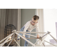 Junge klettert auf Indoor-Klettergerüst im Wohnzimmer