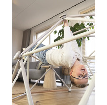 Junge hängt kopfüber an einem Indoor Klettergerüst im Wohnzimmer.