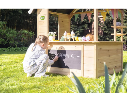 Mädchen schreibt mit Kreide auf einen Holz Kaufladen im Garten.