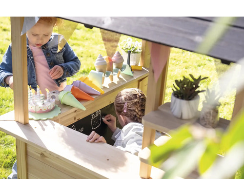 Kinder spielen in einem Kaufladen aus Holz mit Tafel, Eis und Kuchen