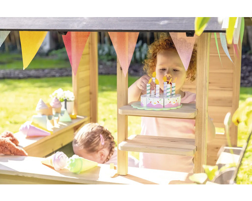 Kinder spielen in einem hölzernen Kaufmannsladen mit Spielzeugessen und einer Girlande.