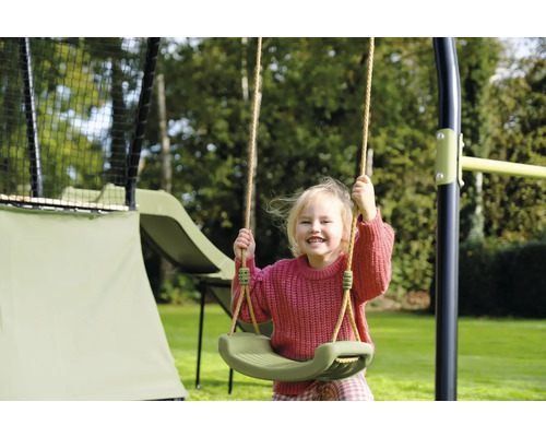 Lachendes Kind auf einer Gartenschaukel vor Trampolin und Rutsche