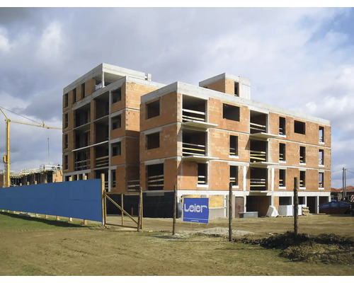 Mehrgeschossiges Rohbaugebäude aus Ziegelsteinen mit Betonabdeckung und Leier Logo.